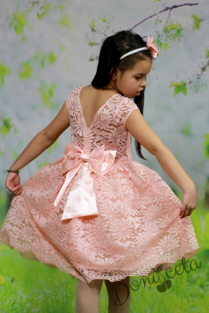 Официална детска рокля от дантела в прасковено с къс ръкав и голяма панделка отзад